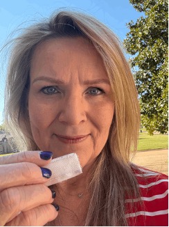 A blonde haired woman wearing a red and white striped shirt holding up a piece of white velcro