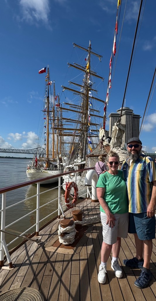 A man and woman standing in front of Sail250 Tall Ships