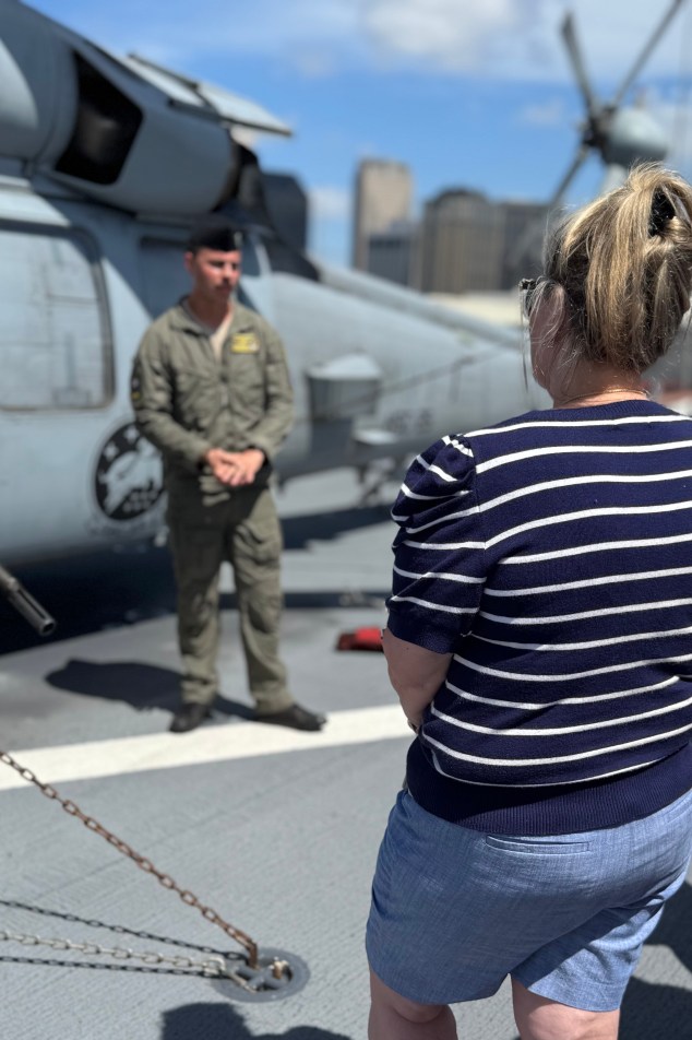 a woman listening to a naval pilot on the flight deck of the USS Kearsarge