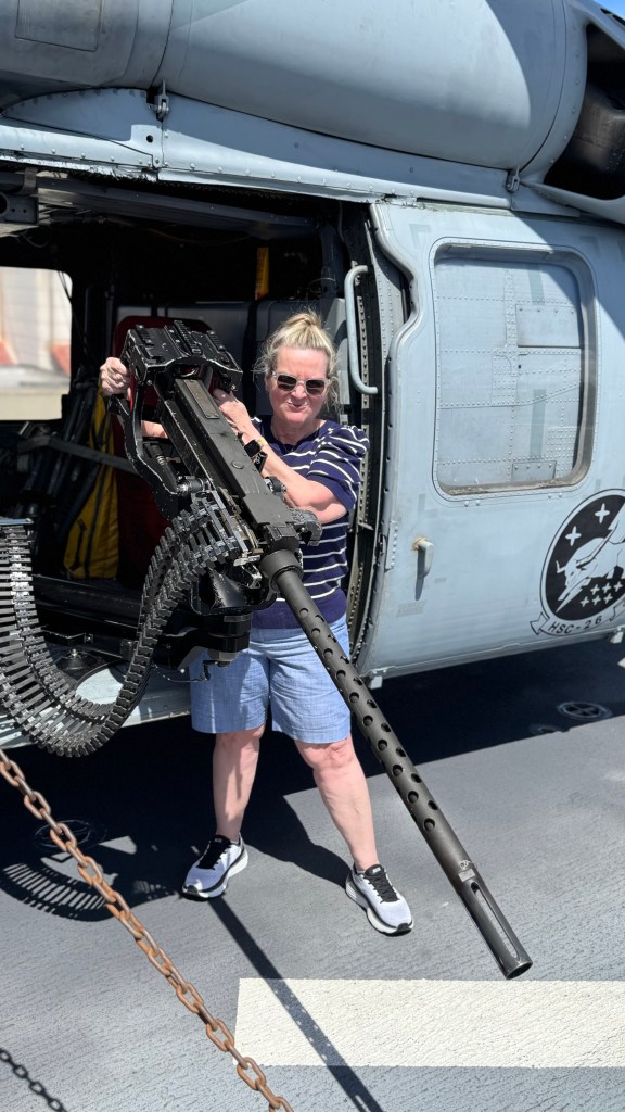 a woman holding a piece of military equipment on the flight deck of the USS Kearsarge