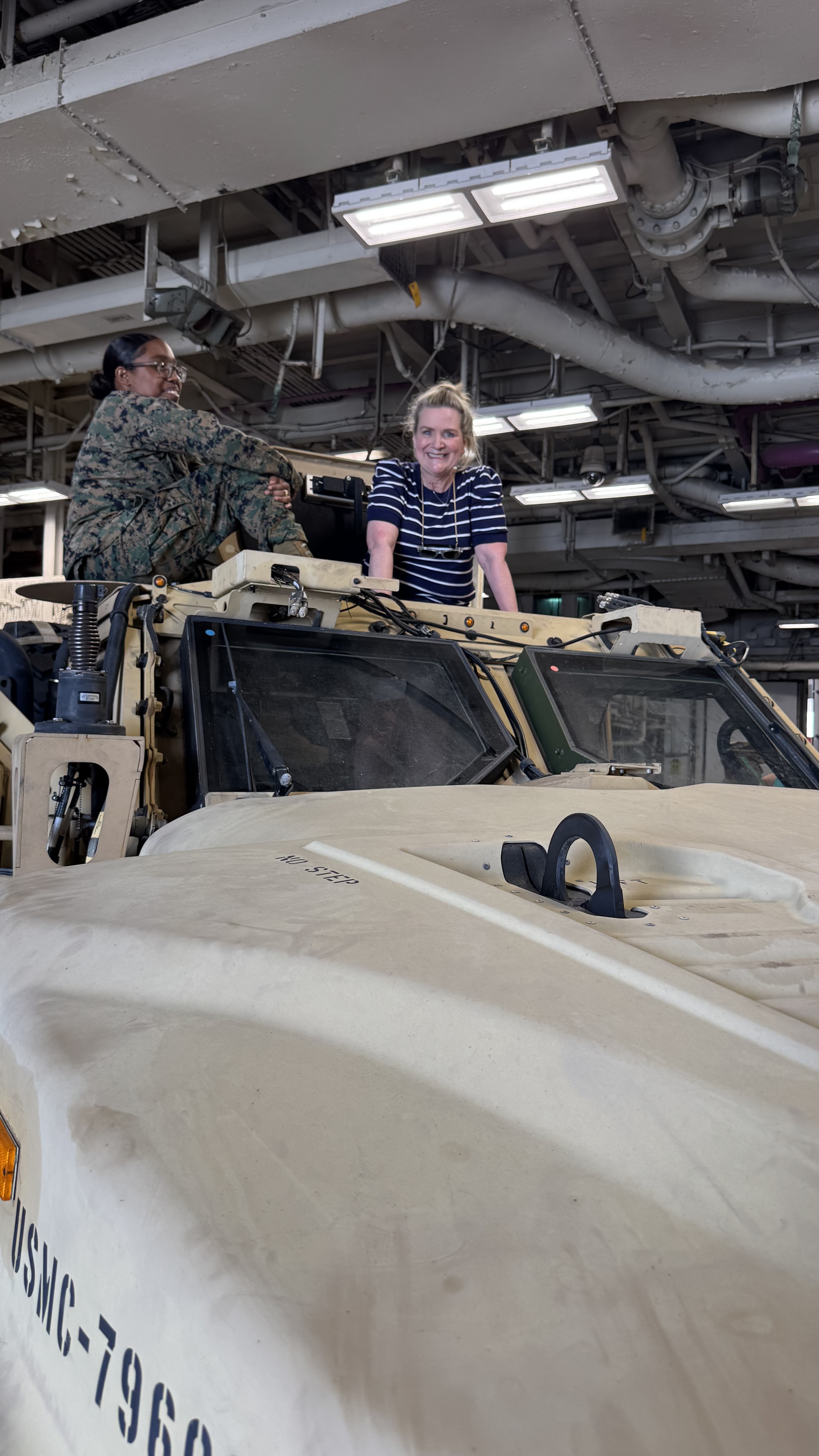 two women atop a military vehicle in the USS Kearsarge