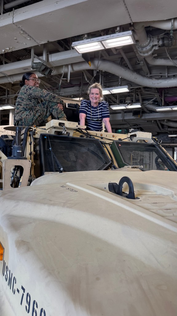two women atop a military vehicle in the USS Kearsarge