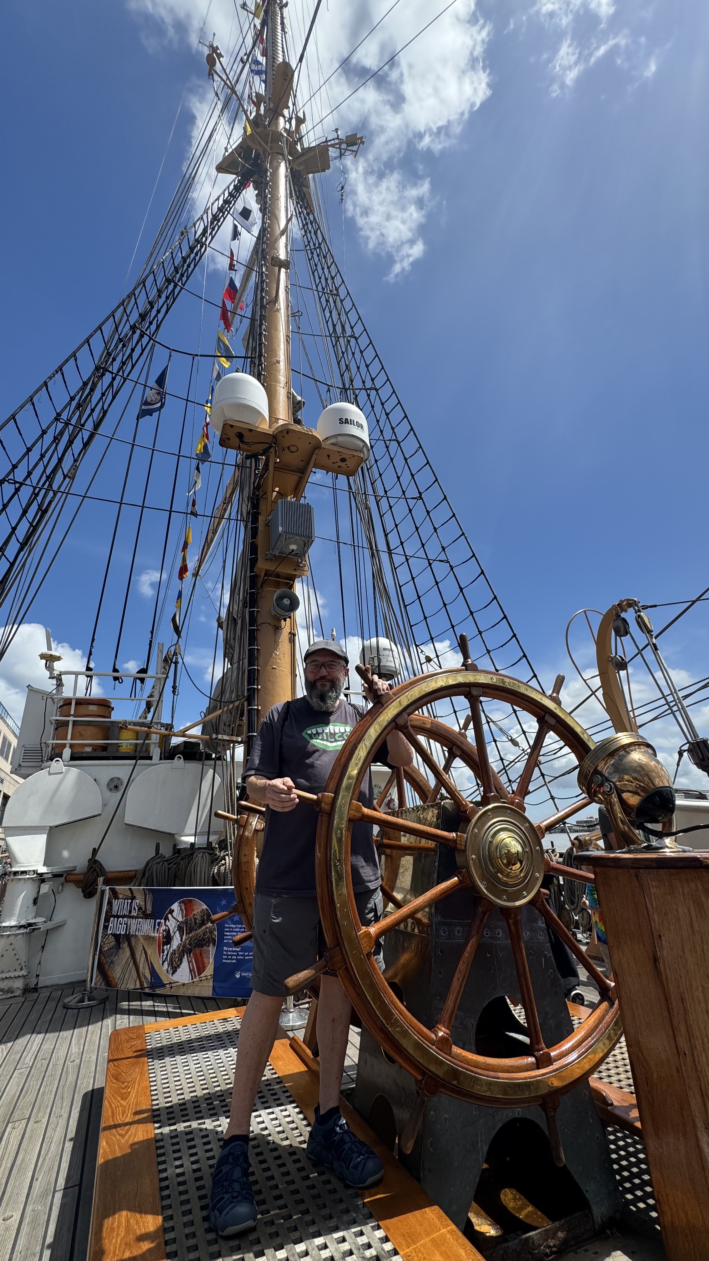 A man standing at the helm of The US Coast Guard Barque Eagle - America's Tall Ship