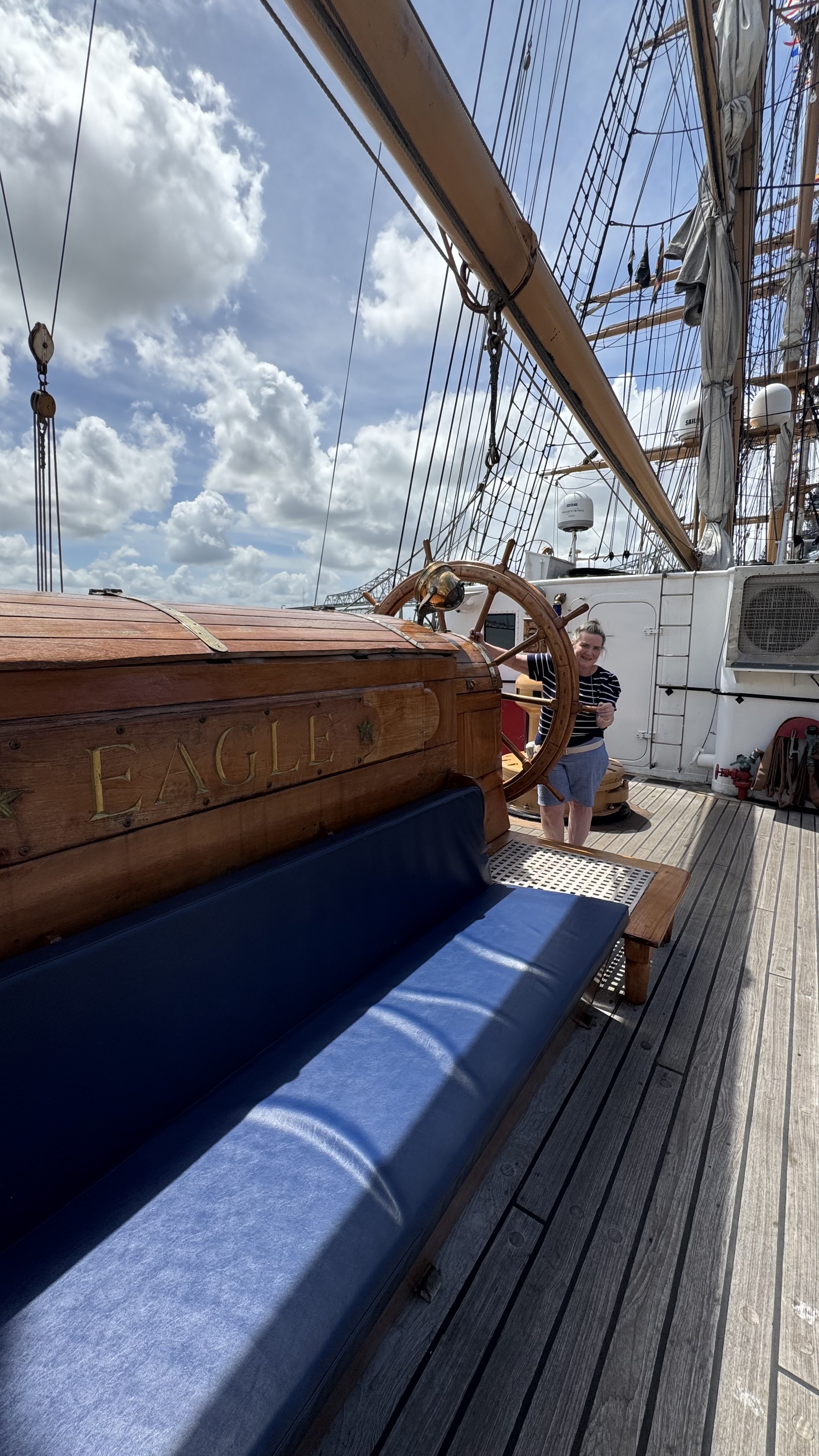 a woman standing at the wheel of The US Coast Guard Barque Eagle - America's Tall Ship
